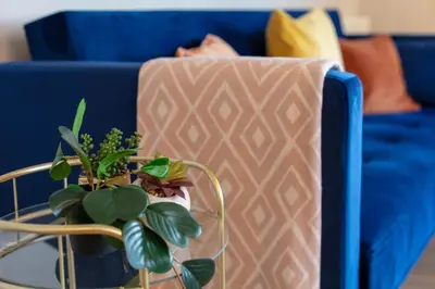 a blue couch with a table with plants on it at Waverley Suite No57 - Donnini Apartments in Ayr