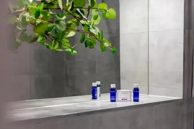 a bathroom counter with three bottles of soap and a mirror at Waverley Suite No57 - Donnini Apartments in Ayr