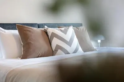 a bed with white and brown pillows on it at Waverley Suite No57 - Donnini Apartments in Ayr