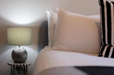 a bedroom with a bed with a lamp on a table at Waverley Suite No57 - Donnini Apartments in Ayr
