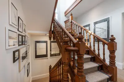 a wooden staircase in a home with pictures on the wall at Tithe Barn - Self Check In Hotel in Cockermouth