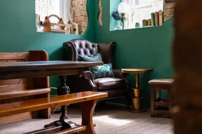 a chair and a table in a room with green walls at Tithe Barn - Self Check In Hotel in Cockermouth