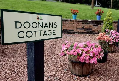 a sign that reads dovenantsate with pots of flowers at Doonans Cottage in Maybole
