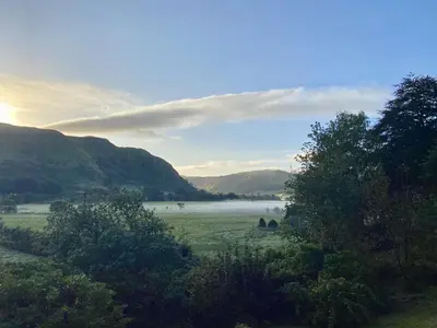 a field with fog in the distance with mountains at Balcraig House in Maybole