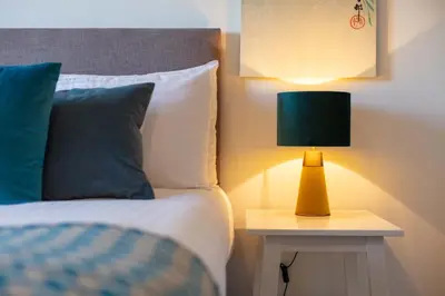 a bedroom with a bed with a lamp on a table at Walker Suite No53 - Donnini Apartments in Kilmarnock