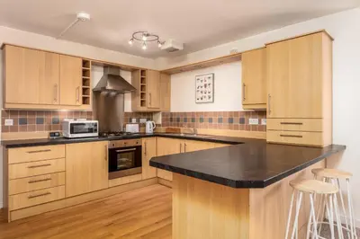 a kitchen with wooden cabinets and a black counter top at Walker Suite No53 - Donnini Apartments in Kilmarnock