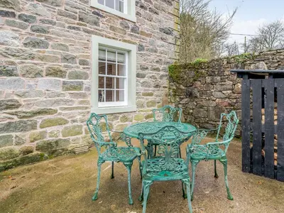 a table and chairs sitting outside of a stone building at Branthwaite Cottage in Caldbeck