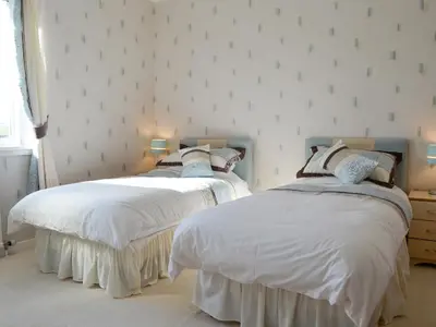 two beds in a bedroom with white sheets at Bel-Mar in Whithorn