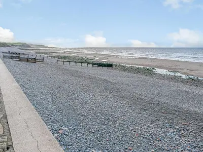 a rocky beach with benches on the side of the ocean at Seacote Gardens in St Bees