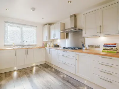a kitchen with white cabinets and a wooden floor at Seacote Gardens in St Bees
