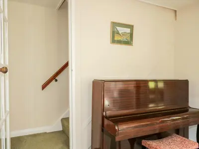 a piano sitting in a hallway next to a staircase at Fell Foot in Holmrook