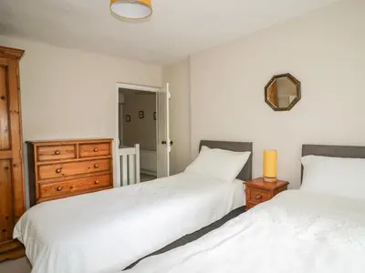 a bedroom with two beds and a dresser and a mirror at Fell Foot in Holmrook