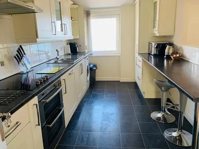 a kitchen with white cabinets and black counter tops at Cunard Apartments in Douglas