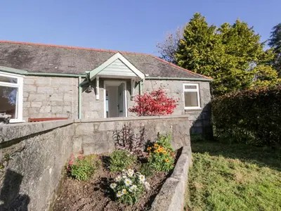 a house with a stone retaining wall and flowers at Old Kiln Cottage in Dumfries