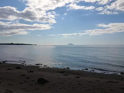 a beach with the ocean and a cloudy sky at Honesty Cottage in Girvan
