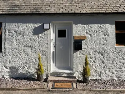 a white house with a white door and a sign at Terraughtie Cottage East-Uk31767 in Terreglestown