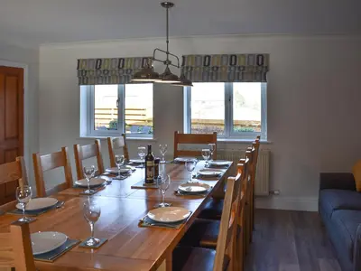 a dining room table with chairs and a long table with wine glasses at Chapel House in Dearham