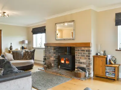 a living room with a brick fireplace with a mirror at Chapel House in Dearham