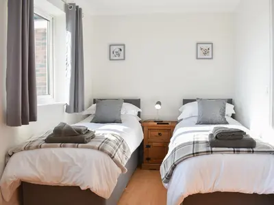 two beds in a room with white walls and windows at Chapel House in Dearham