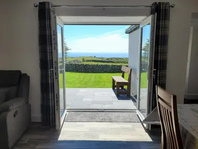 an open door to a patio with a view at Garrarie Cottage in Monreith