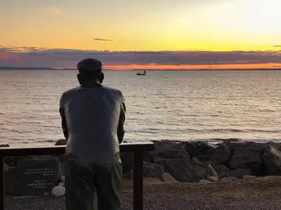 a man sitting on a bench looking out at the ocean at Garrarie Cottage in Monreith