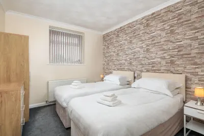 two beds in a room with a brick wall at Four Oaks House in Carlisle