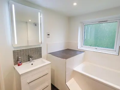 a white bathroom with a sink and a window at Kiln How in Keswick