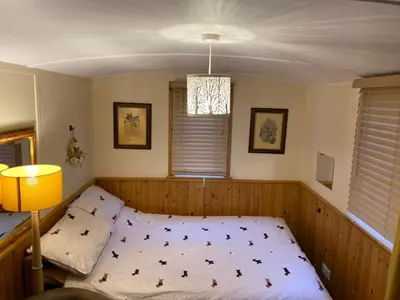 a bedroom with a bed and a lamp and a window at Shepherds Hut-hot tub hire-dog friendly-views in Dumfries