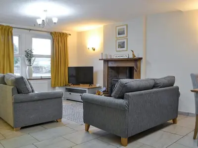a living room with two couches and a television at Holly Cottage in Cockermouth
