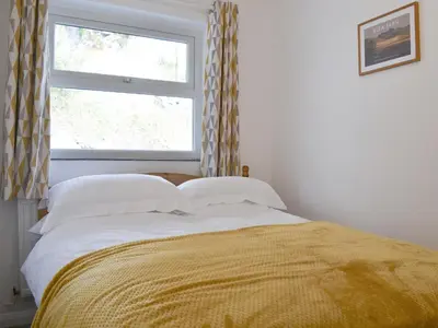 a bed with a yellow blanket and a window at Langdale Cottage in Chapel Stile