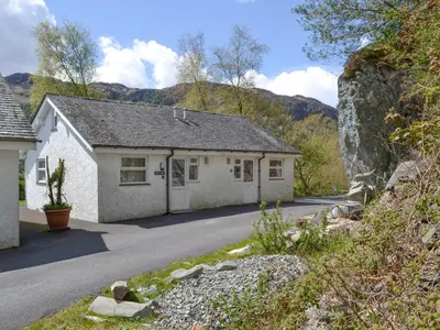 a small white house with a mountain in the background at Langdale Cottage in Chapel Stile