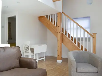 a living room with a staircase and a chair at Langdale Cottage in Chapel Stile