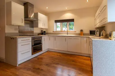 a kitchen with white cabinets and a wooden floor at The Lookout Keswick in Keswick