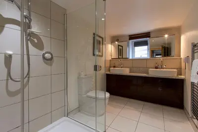 a bathroom with a glass shower and two sinks at The Lookout Keswick in Keswick
