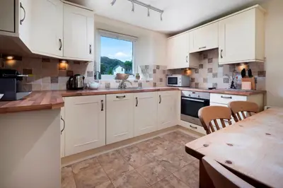 a kitchen with white cabinets and a wooden table at Meadow View Chapel Stile in Chapel Stile