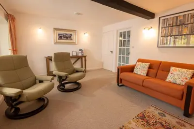 a living room with an orange couch and two chairs at Pippins, Elterwater in Chapel Stile
