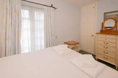 a bedroom with a white bed and a dresser and a mirror at 2 Bridge Syke, Elterwater in Chapel Stile