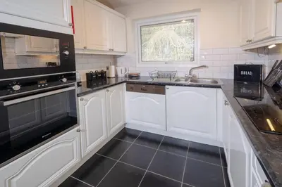 a kitchen with white cabinets and a black floor at 27 Thrang Brow, Chapel Stile in Chapel Stile