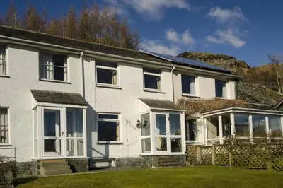 a white house with white windows and a yard at 27 Thrang Brow, Chapel Stile in Chapel Stile