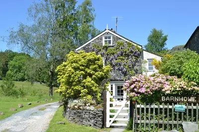 a white house with a white fence and flowers at Barnhowe, Elterwater in Chapel Stile