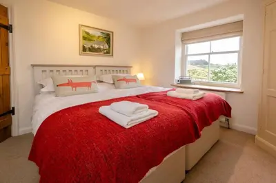 a bedroom with a large bed with a red blanket at Barnhowe, Elterwater in Chapel Stile