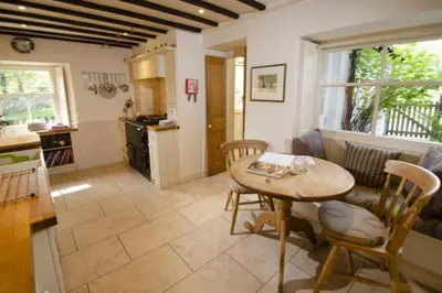 a living room with a table and a kitchen at Barnhowe, Elterwater in Chapel Stile