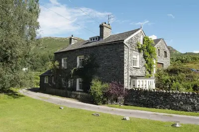 a black brick house with a stone wall at Barnhowe, Elterwater in Chapel Stile