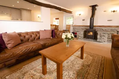 a living room with a leather couch and a fireplace at End Cottage, Chapel Stile in Chapel Stile