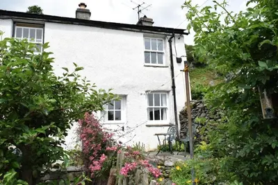 a white cottage with flowers in front of it at Inglewood Cottage, Chapel Stile in Chapel Stile