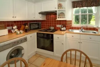 a kitchen with white cabinets and a sink and a dishwasher at Inglewood Cottage, Chapel Stile in Chapel Stile