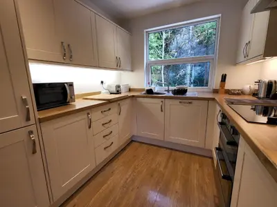 a kitchen with white cabinets and a window at Lingmell Fell View, Chapel Stile in Chapel Stile