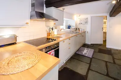 a kitchen with white cabinets and a wooden counter top at Priest End, Chapel Stile in Chapel Stile