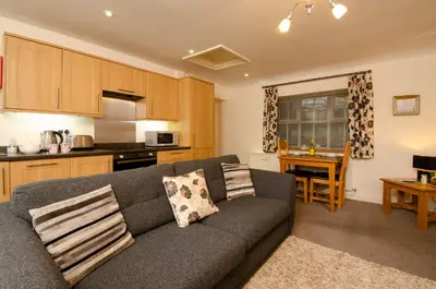 a living room with a couch and a kitchen at Rosegate Cottage, Elterwater in Elterwater