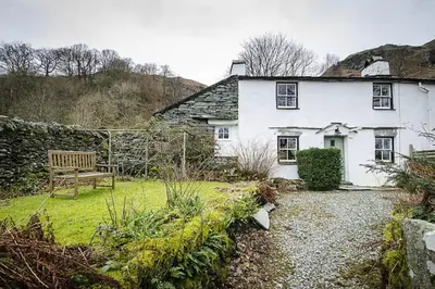 a white house with a bench in a garden at Speddy Cottage, Chapel Stile in Chapel Stile